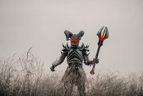 Mutante guerrero camina en el prado con los ojos brillantes y sostiene la maza en sus manos. - Foto, imagen
