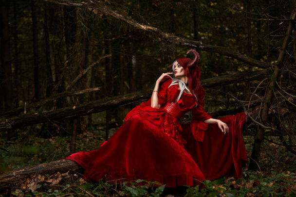 神秘的な森の中でマレフィセントポーズのイメージでスタイリッシュでファッショナブルなモデルの女の子-おとぎ話、コスプレ。ハロウィン - 写真・画像
