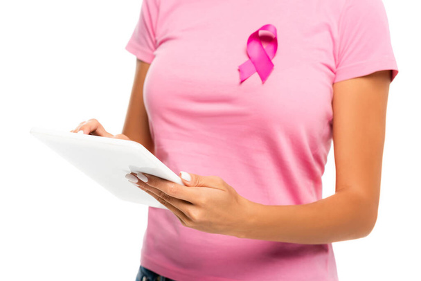乳癌意識のリボンを身に着けている間デジタルタブレットを使用して女性の切り取られたビュー白に隔離された背景にぼやけた - 写真・画像