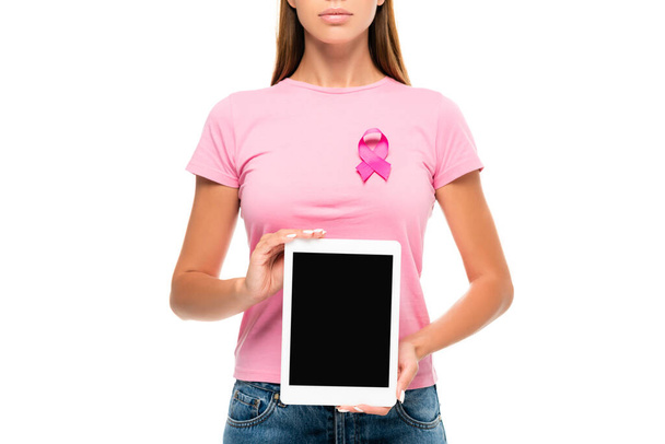 Προβολή της νεαρής γυναίκας με κορδέλα ευαισθητοποίησης για τον καρκίνο του μαστού κρατώντας ψηφιακό δισκίο με λευκή οθόνη απομονωμένη σε λευκό - Φωτογραφία, εικόνα
