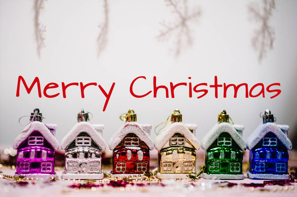 Text Merry Christmas, concept. Christmas tree decorations in form of colored traditional europe houses, snowflakes. New Year city banners. blurred. Festive background, Happy New Year 2018. - Fotó, kép