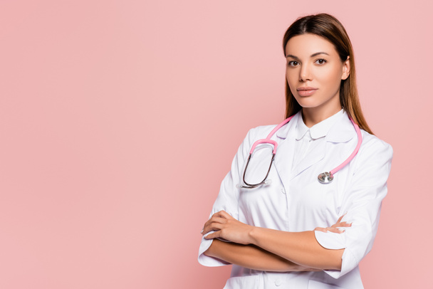 Young doctor in white coat and stethoscope looking at camera isolated on pink - Фото, зображення