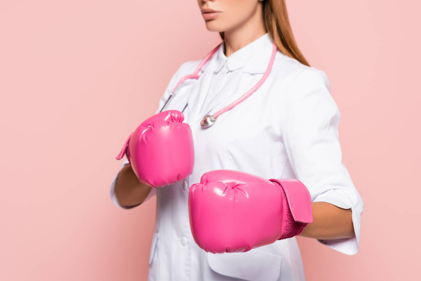 Vista recortada do médico em luvas de boxe e casaco branco sobre fundo borrado isolado em rosa - Foto, Imagem