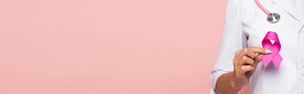 Vista parcial do médico com estetoscópio segurando fita de consciência de câncer de mama isolado em rosa, banner  - Foto, Imagem