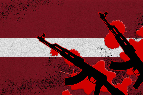 Flaga Łotwy i dwa czarne karabiny AK-47 w czerwonej krwi. Koncepcja ataku terrorystycznego lub operacji wojskowych ze skutkiem śmiertelnym. Niebezpieczne użycie broni - Zdjęcie, obraz