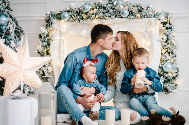 The dad, mom hug little son and daughter near Christmas tree. Happy New Year and Merry Christmas. Christmas decorated interior. The concept of family holiday. Close up. - Foto, imagen