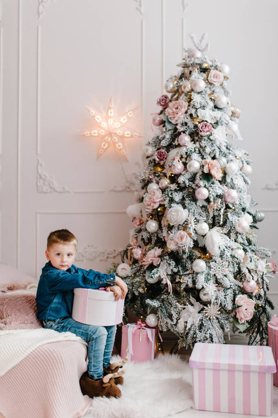 The boy with presents, gifts near Christmas tree. Happy New Year and Merry Christmas. Christmas decorated interior. The concept of family winter holiday. - Foto, Imagem