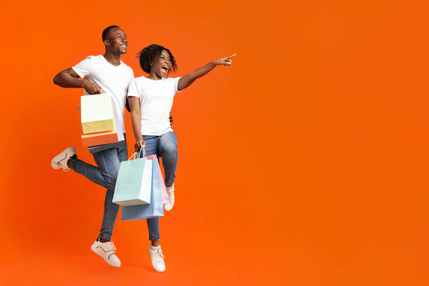 Чорний чоловік і жінка з покупками, вказуючи на порожній простір
 - Фото, зображення