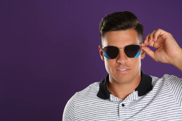 Красивый мужчина в солнечных очках на фиолетовом фоне. Пространство для текста - Фото, изображение