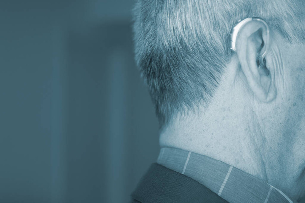 vieil homme blanc caucasien portant une aide auditive numérique moderne dans l'oreille avec des cheveux gris. - Photo, image