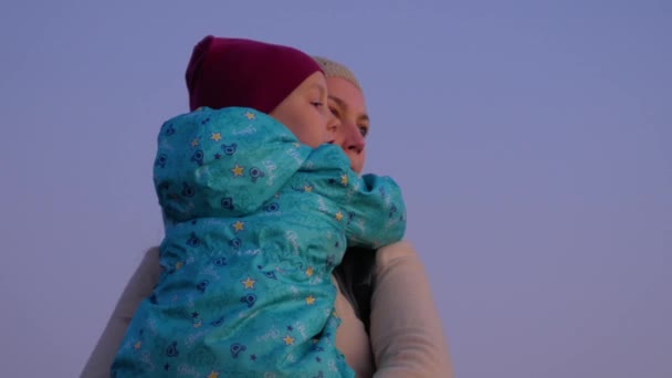 Madre e figlia in piedi sul paesaggio della città di sera. Una bambina che abbraccia e bacia la mamma al tramonto all'aperto. Amore bambino abbraccia coccola la sua mamma. Biglietto di auguri per la festa della mamma. Stile di vita 4K - Filmati, video