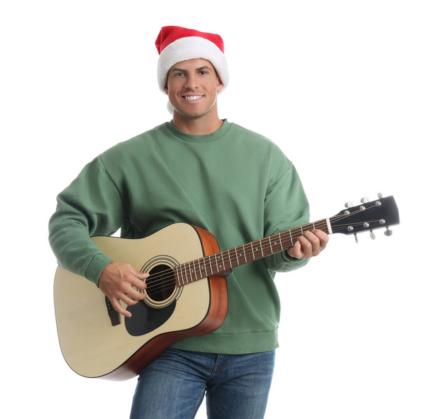 Mann mit Weihnachtsmütze spielt Akustikgitarre auf weißem Hintergrund. Weihnachtsmusik - Foto, Bild