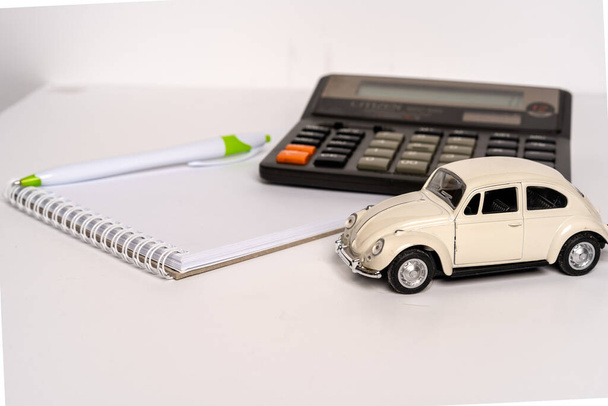 Speelgoedauto en rekenmachine met berekeningen, het concept van de verkoop en het kopen van auto - Foto, afbeelding
