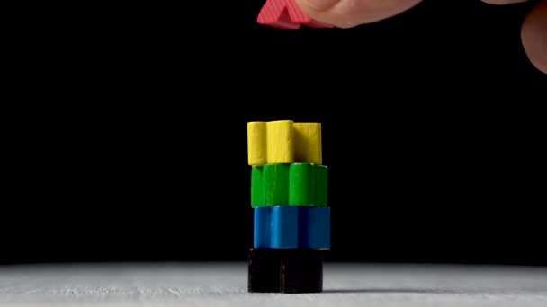 hand establishes a red figurine on top of the pyramid structure from other multi-colored figures. Leadership and teamwork concept. Slow motion. Close-up - Séquence, vidéo
