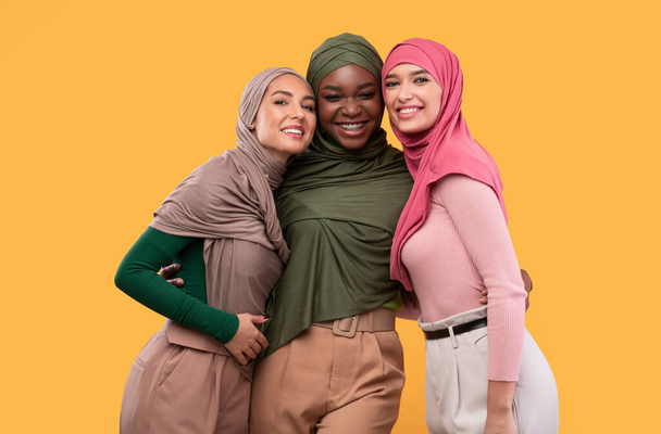 Tre belle donne islamiche in Hijab in posa su sfondo giallo - Foto, immagini