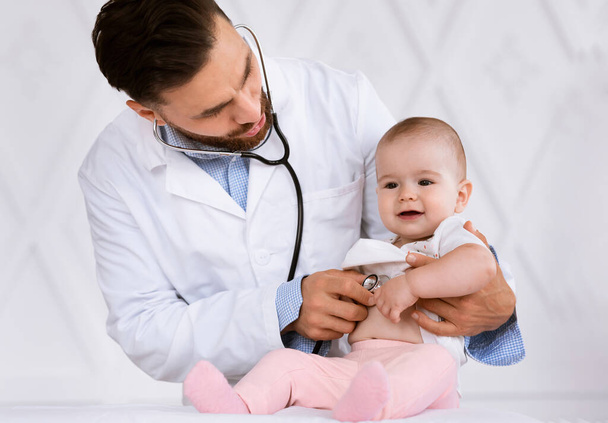 Lekarz badający dziecko słuchające bicia serca stetoskopem w klinice - Zdjęcie, obraz