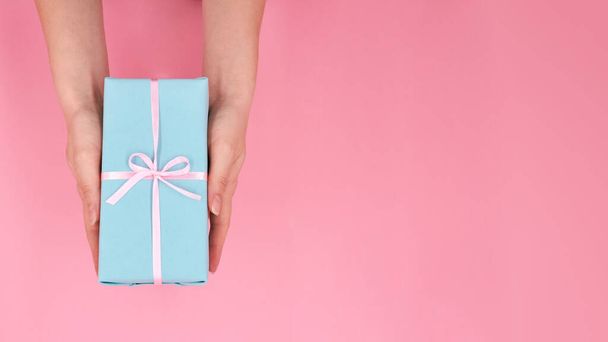 Una donna che tiene in mano la scatola regalo di Natale o Capodanno su uno sfondo rosa con spazio per la copia - Foto, immagini