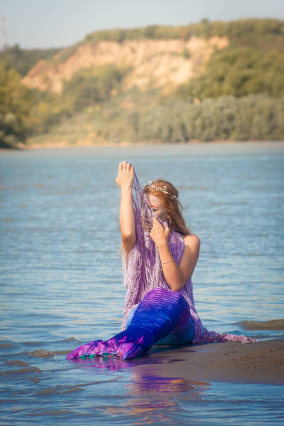 Girl with a mermaid tail on the river bank. Mystical and fairytale heroine. A sensation on vacation. The water has cleared - 写真・画像
