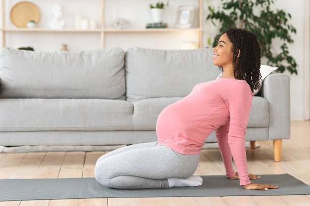 Mujer negra embarazada activa haciendo ejercicio en casa, haciendo yoga - Foto, Imagen
