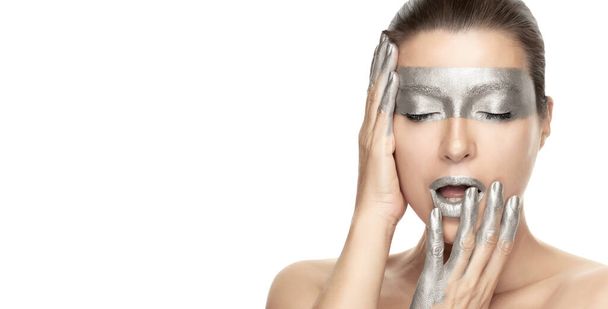Silver skin makeup. Skincare treatment concept. Beautiful model girl with silver makeup gracefully holding her hands to her face. Beauty portrait isolated on white with copyspace in a panorama banner. - Photo, Image