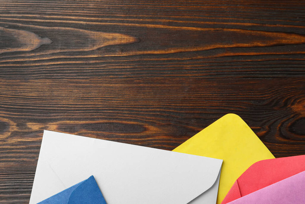 Colorful paper envelopes on wooden background, flat lay. Space for text - Фото, зображення