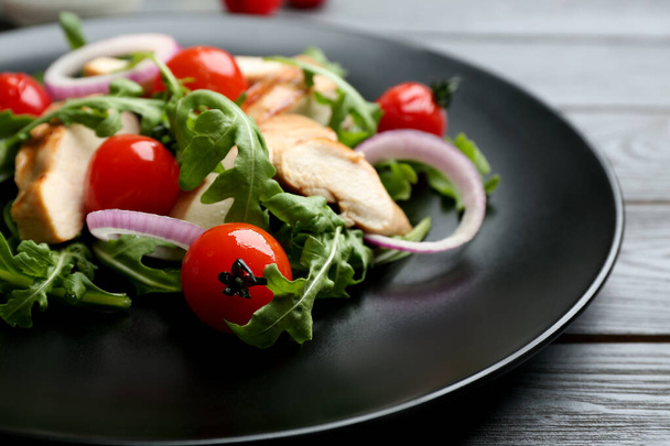 Delicious salad with chicken, vegetables and arugula  on grey table, closeup - Фото, зображення