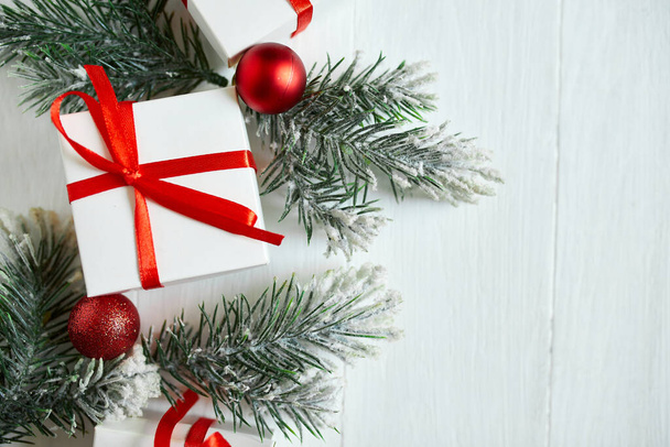 Рождественская подарочная коробка, елка ветки, красные украшения на белом деревянном фоне, Рождество, зима, новогодняя концепция, плоский уголок, вид сверху, копировальное пространство - Фото, изображение