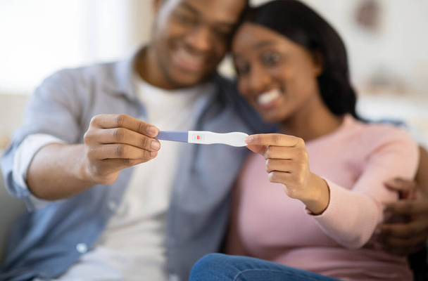 Jeune couple balck montrant un test de grossesse positif à la maison, accent sélectif sur les mains - Photo, image