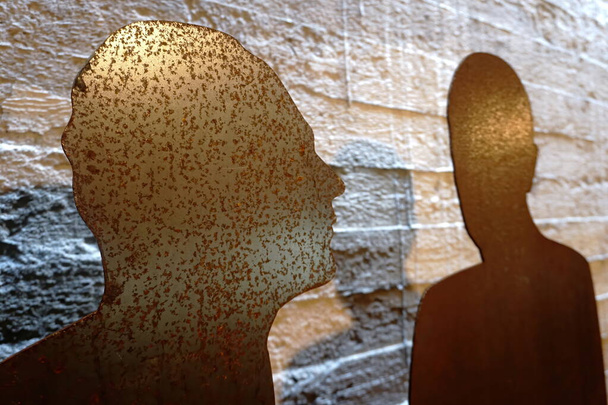 Two rusty metal plate as a human silhouette on a rough concrete wall background. Two people silhouette.                                - Photo, Image