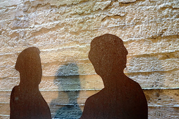 Two rusty metal plate as a human silhouette on a rough concrete wall background. Two people silhouette.                                - Photo, Image