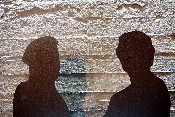 Due piastre di metallo arrugginito come una silhouette umana su uno sfondo muro di cemento grezzo. Due persone silhouette.                                - Foto, immagini
