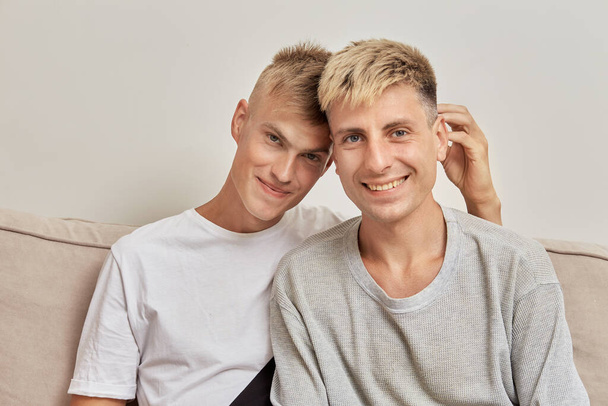 Portrait of two beautiful blond guys sitting at home on the sofa. - Foto, Imagem