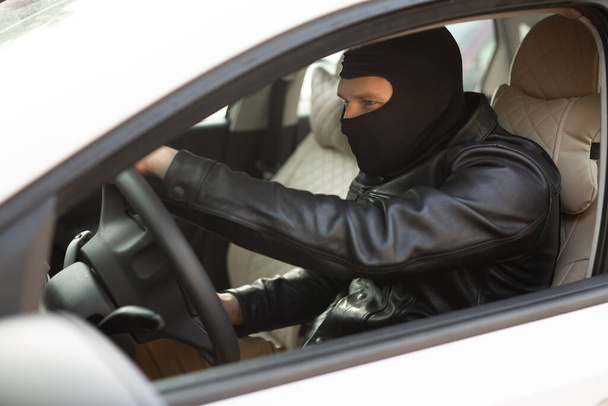 gangster in a black mask steals someone else's car - Фото, изображение