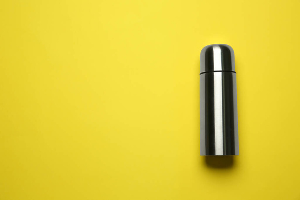 Stainless steel thermos on yellow background, top view. Space for text - Фото, зображення