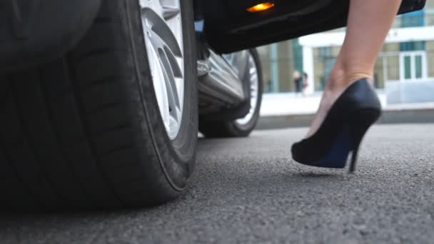 Feet of beautiful girl in black shoes on high heels comes in a back seat of automobile. Young businesswoman open the door and getting into the modern car. Low angle view Close up Slow motion - Footage, Video