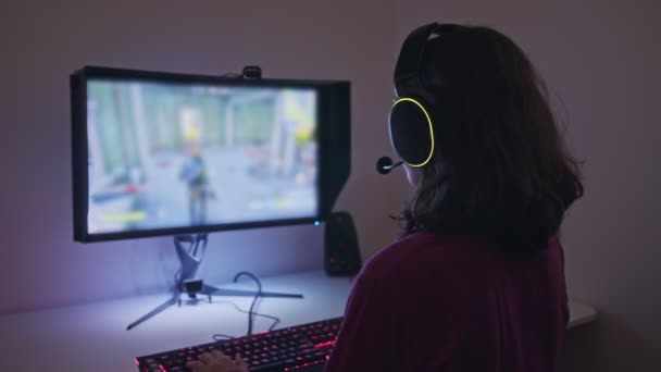 Adolescente sentada frente a una computadora, jugando a un juego con auriculares - Imágenes, Vídeo