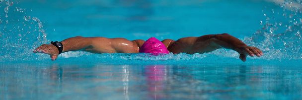 Zwemwedstrijd zwemmer atleet doet vlinder beroerte in zwembad - Foto, afbeelding