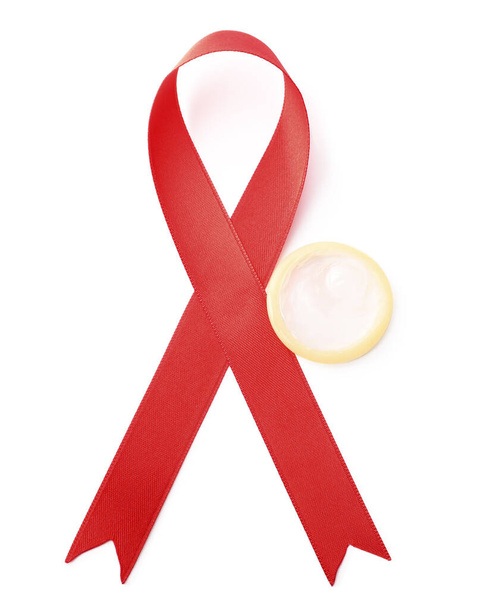 Red ribbon and condom isolated on white, top view. AIDS disease awareness - Foto, Imagen