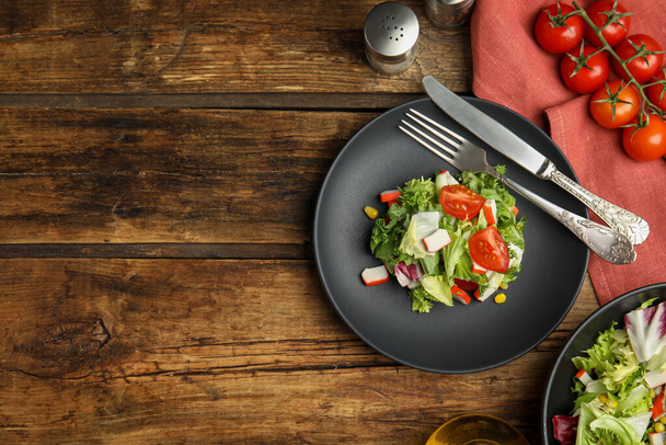 Delicious salad with crab sticks and tomatoes served on wooden table, flat lay. Space for text - Fotoğraf, Görsel