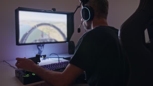Bilgisayarda uçuş simülatörü çalan, kulaklık takan bir adam. - Video, Çekim