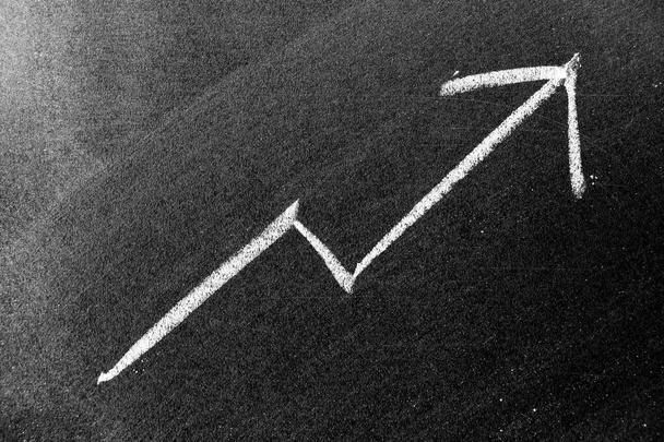 White chalk draw as upward arrow graph on black board background (Concept for sale, profit, cost of company in uptrend) - Foto, Imagen