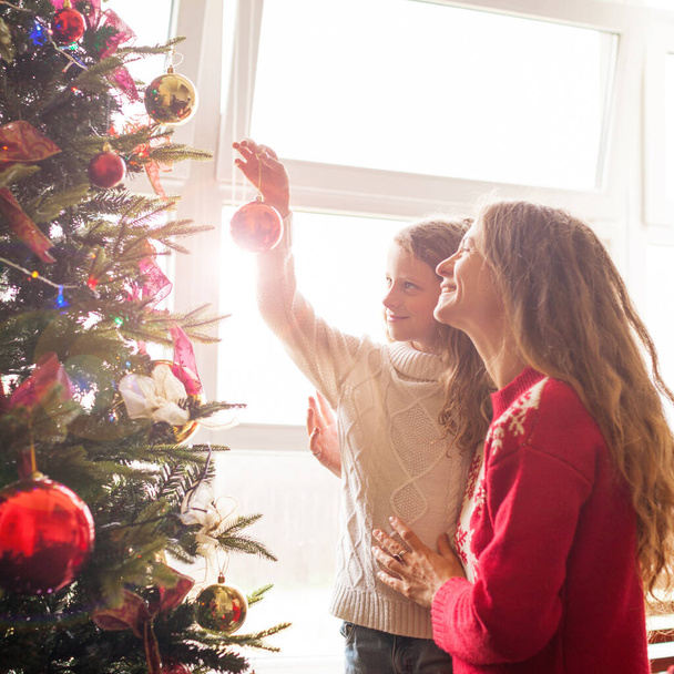 Mom and daughter decorate the Christmas tree - Foto, imagen