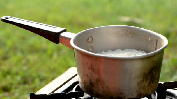 Detailní záběr malého hrnce na vaření rýže s párou na plynovém hořáku při snídani v kempu. Tradiční vaření. Koncept životního stylu v dovolené. - Záběry, video