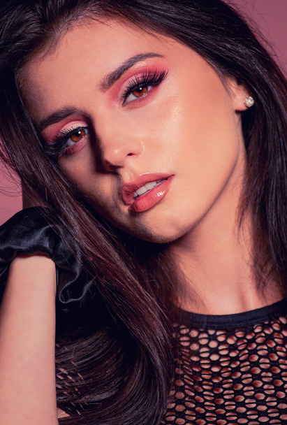 aantrekkelijke brunette met roze make-up op roze achtergrond - Foto, afbeelding