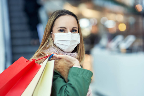Portrait of adult woman shopping in mall wearing a mask, coronavirus concept - Foto, immagini