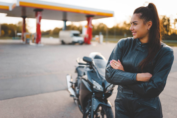 Biker girl in a leather suit near her motorcycle - Photo, Image