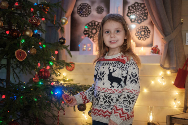 クリスマスツリーの北欧のセーターのかわいい女の子。クリスマスと新年の家族のお祝いの概念 - 写真・画像