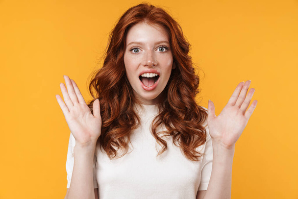 Image of ginger excited girl expressing surprise on camera isolated over yellow background - Φωτογραφία, εικόνα