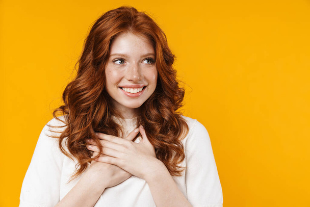 Image of ginger excited girl expressing surprise with hands on her chest isolated over yellow background - Фото, зображення