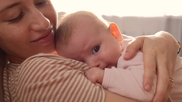 Madre caucasica con lentiggini sorridenti mentre tiene la figlia sul petto e la abbraccia - Filmati, video